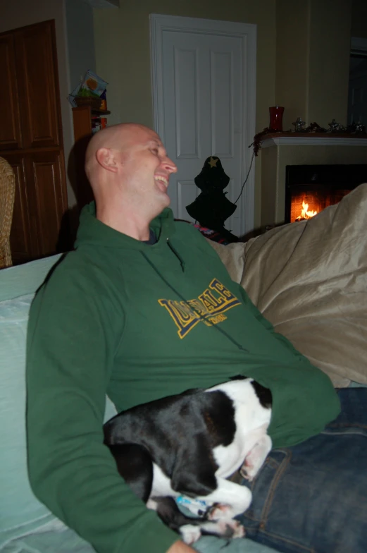 a man laying down holding a dog in his lap
