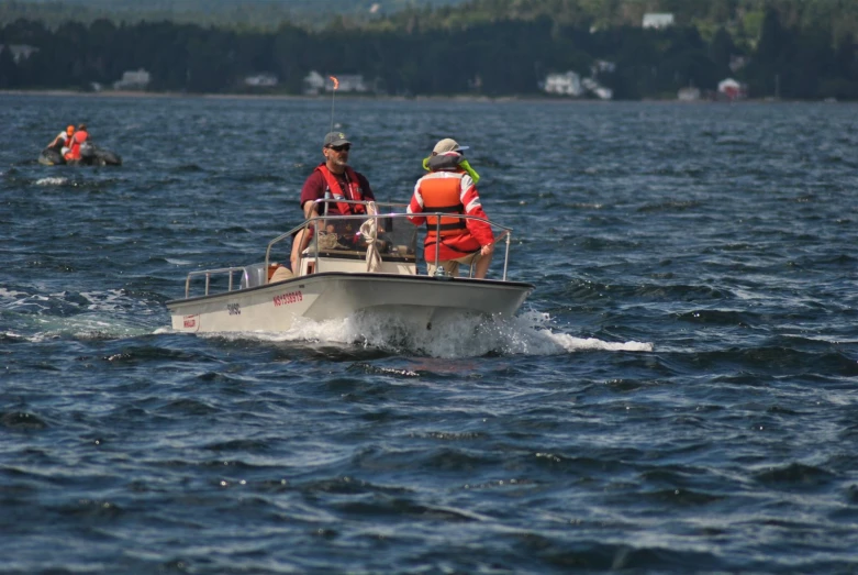 two people in lifejackets and vests riding on a small boat