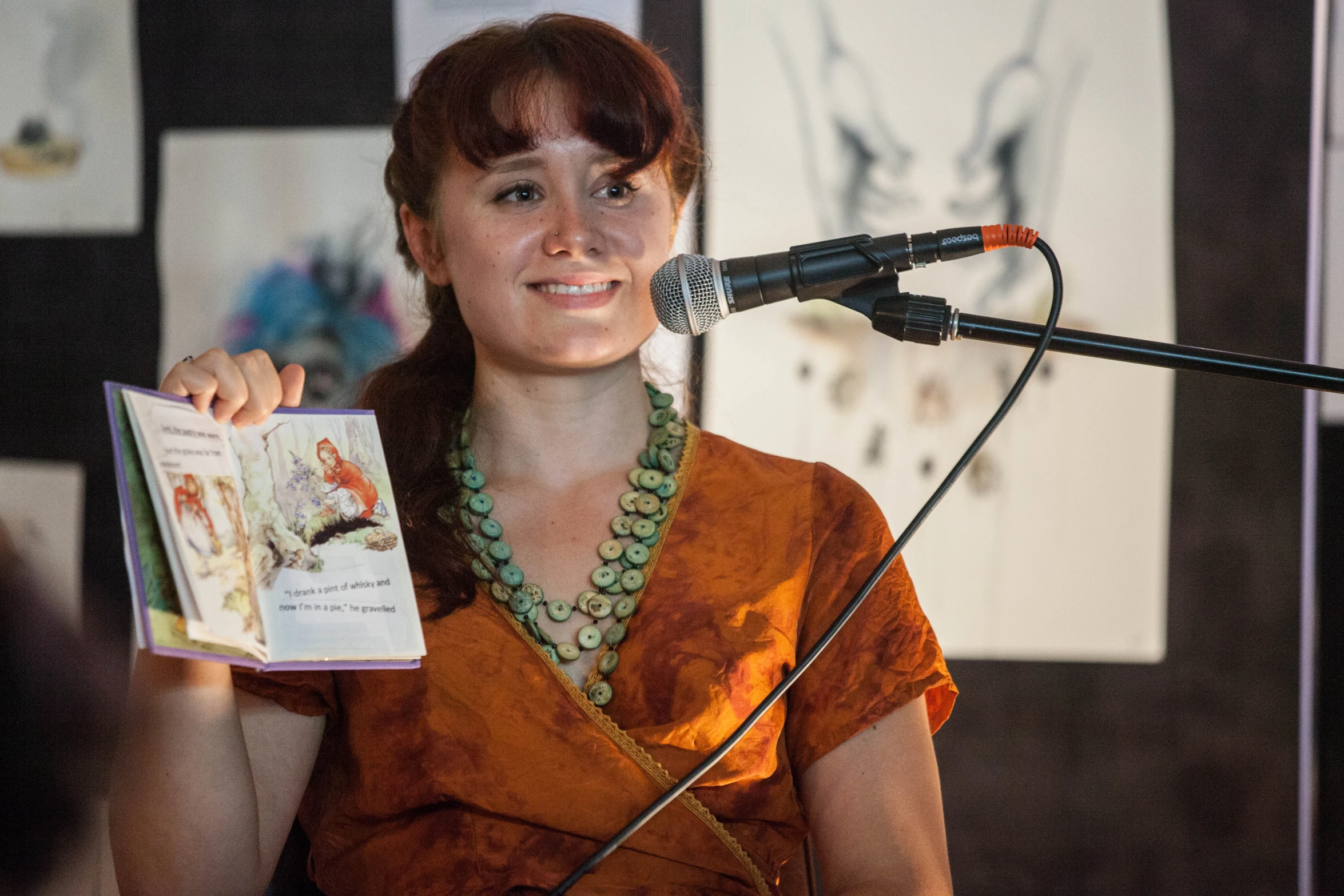 a woman in an orange shirt standing behind a microphone with an open magazine