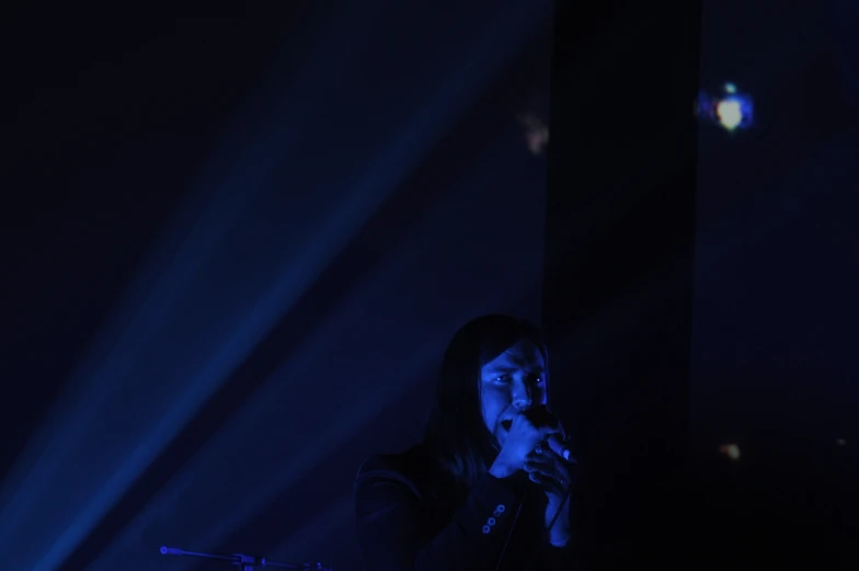 a woman singing at a concert with blue lighting behind her