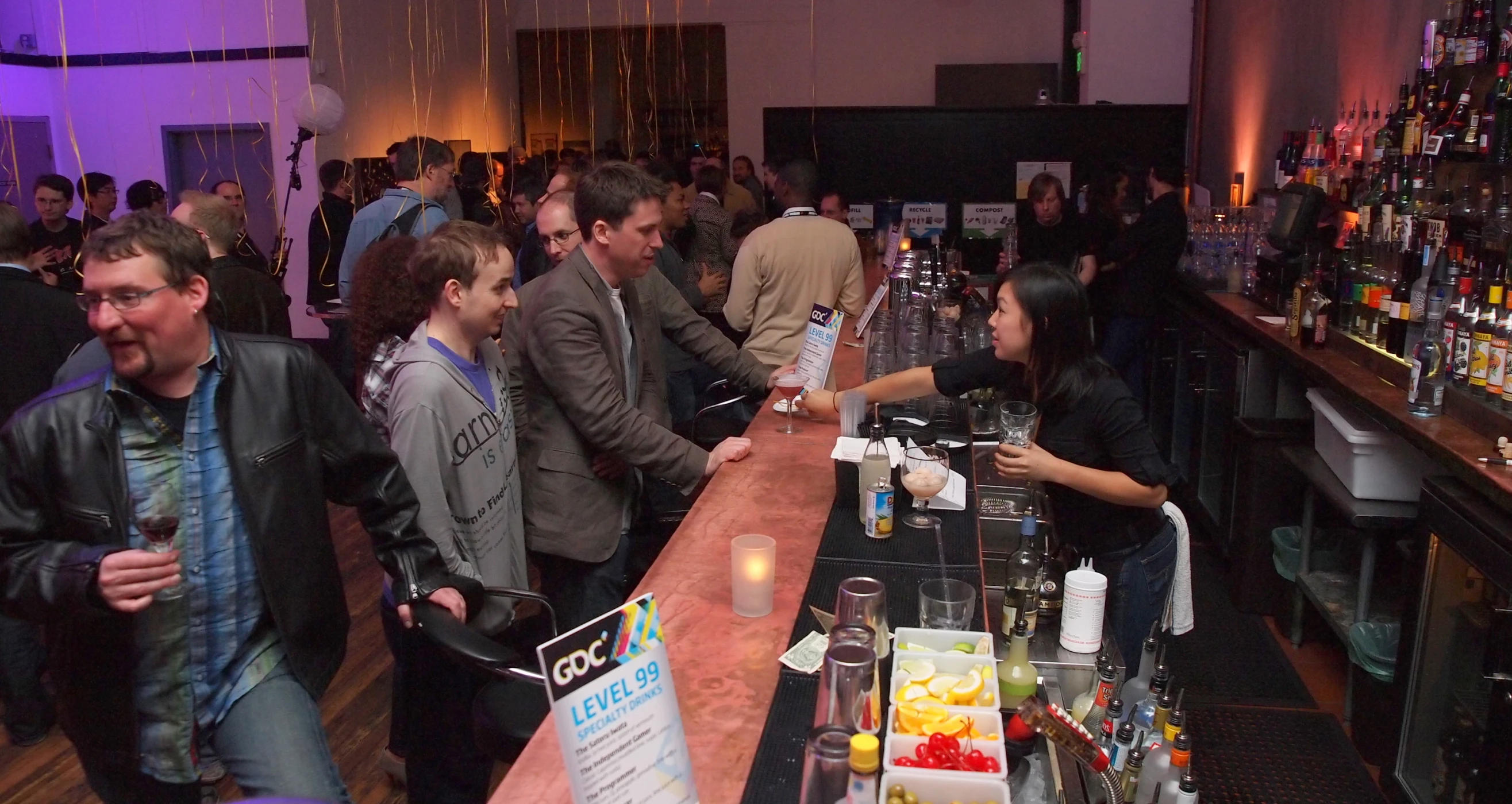 the group of people is gathered around the bar to drink