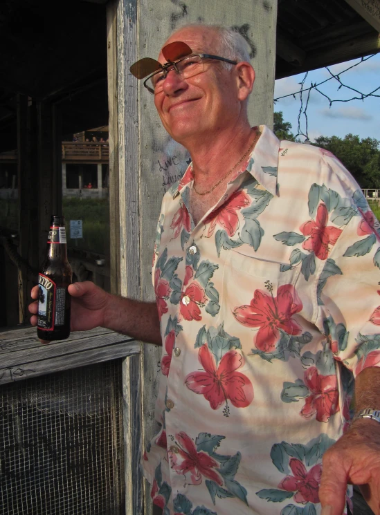 an elderly man with a hawaiian shirt on holding a beer