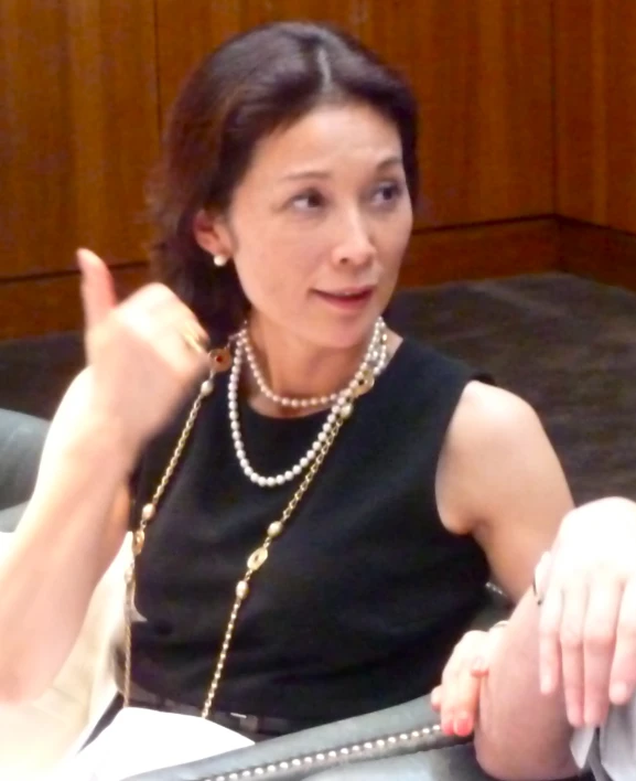 a woman wearing pearls and black talking