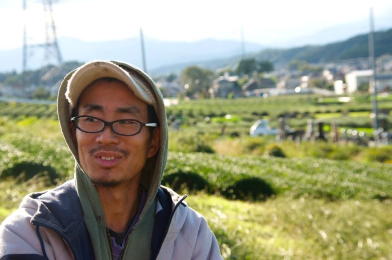 man in glasses standing on a hillside with power lines behind him