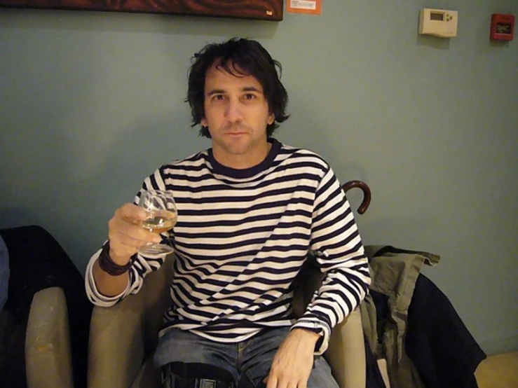 a man holding a wine glass in his hand sitting down