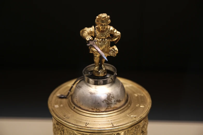 small gold figurine with handle on the bottom of it