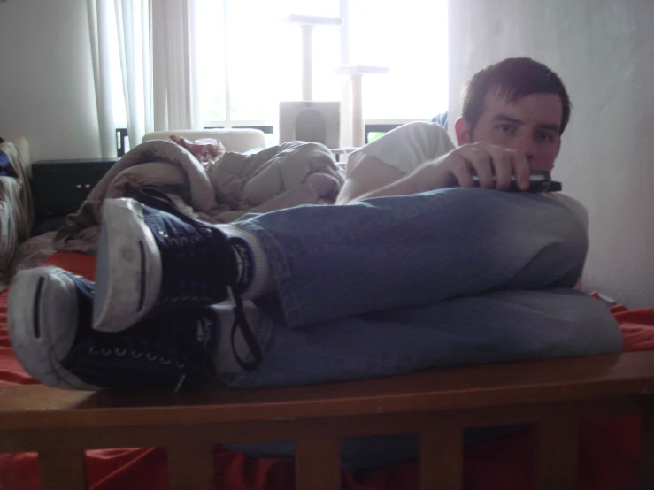 a young man laying on a bed while holding his foot in his mouth