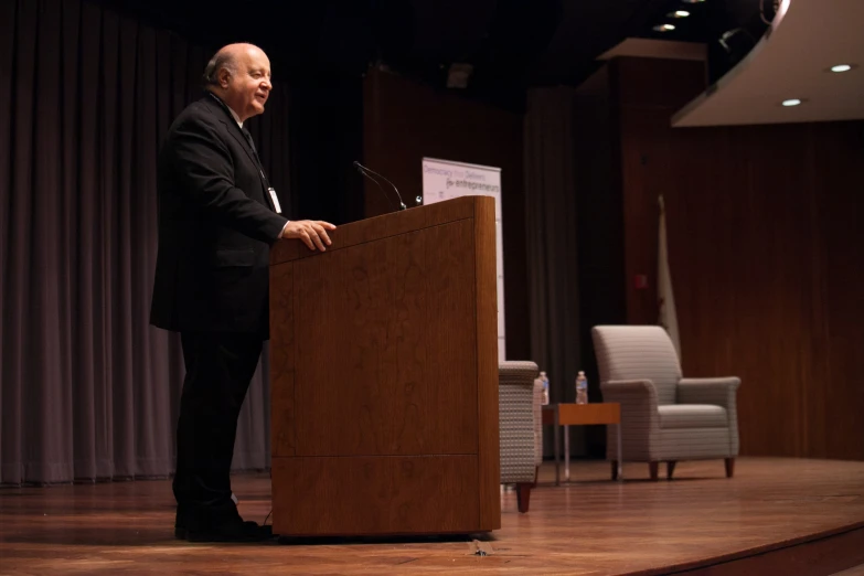 a man is speaking in front of microphone on stage