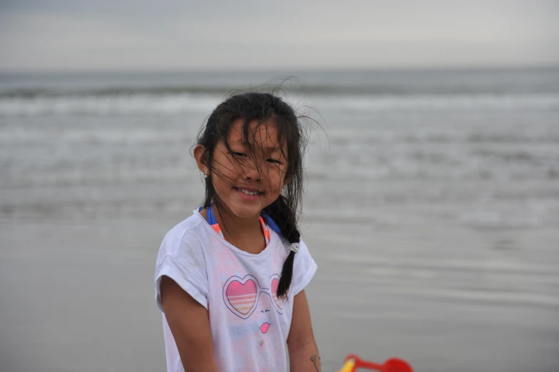 an asian girl with black hair standing on the beach