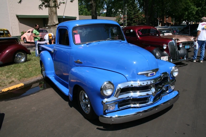 the old blue truck is parked on the street