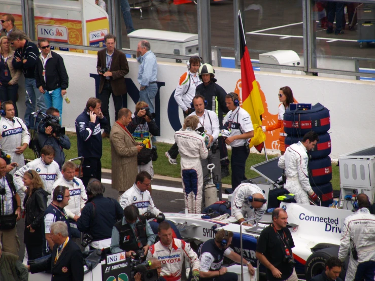 a man holding a white race car in front of people