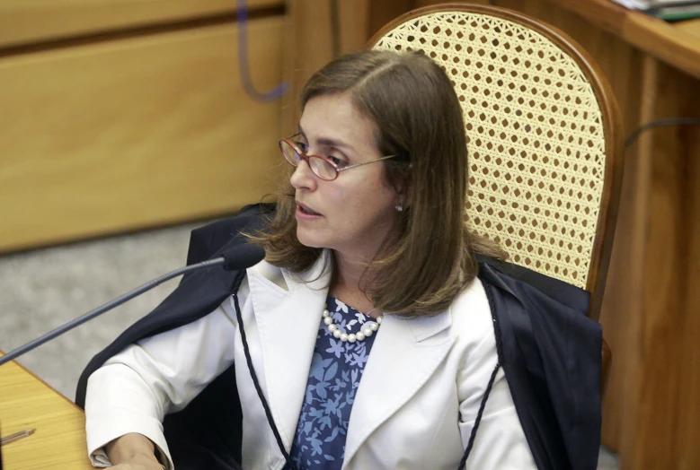 a woman wearing glasses sits at a table