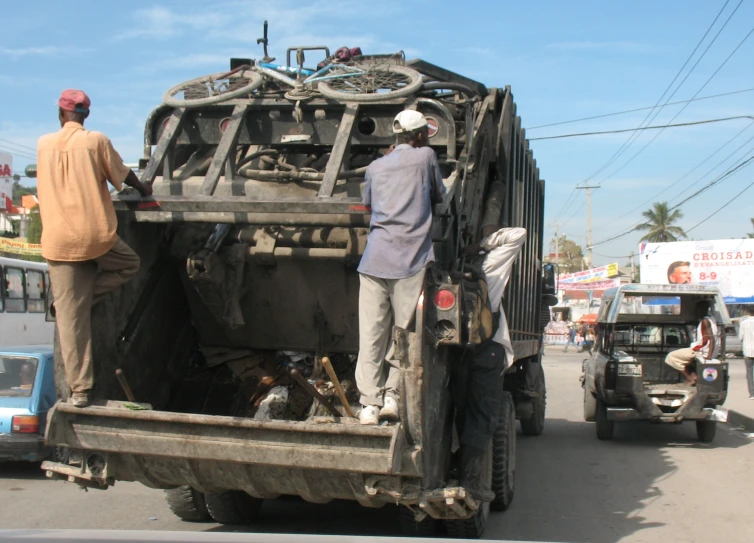 a group of men standing on the back of an old truck