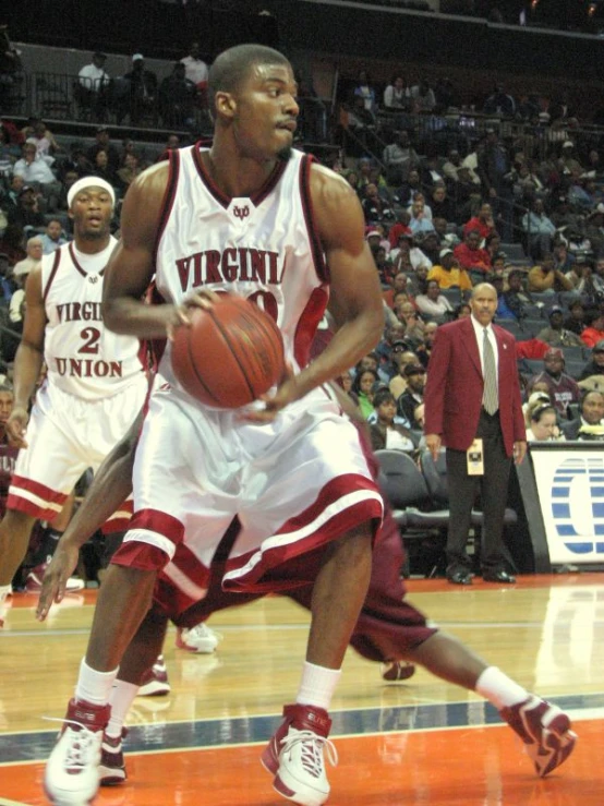 two young men wearing jerseys playing basketball on a court