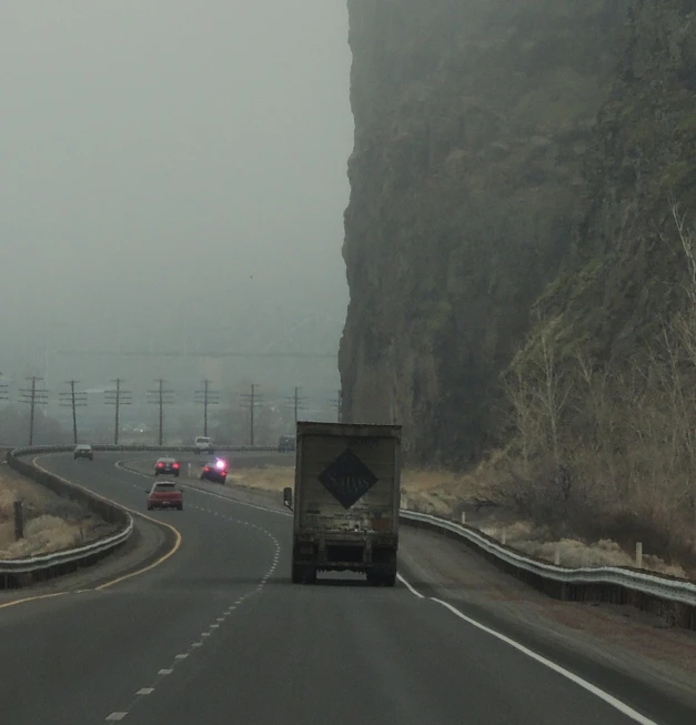 two trucks driving on a rural road on a foggy day