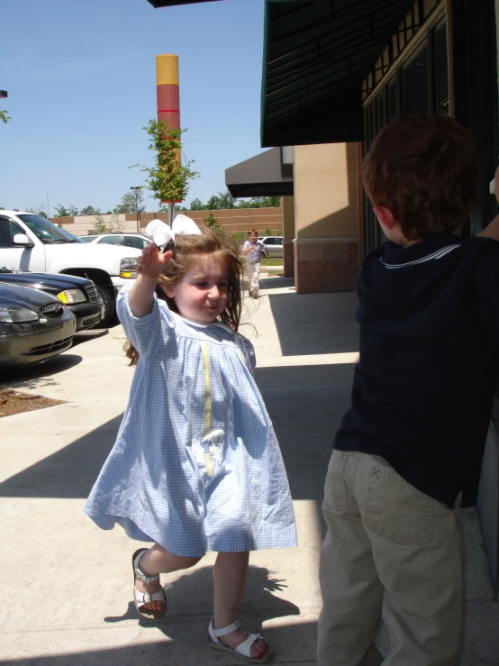 a little girl reaching out to a boy outside