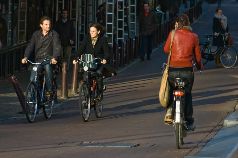 three people on bicycles on the road with people in the background