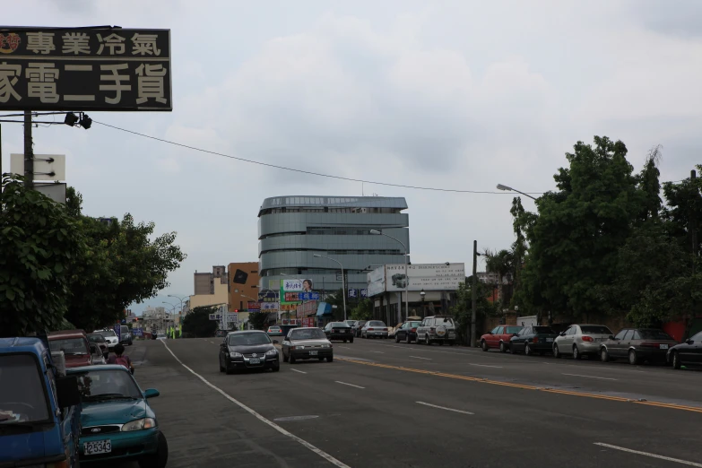 many cars are parked on the street near a tall building