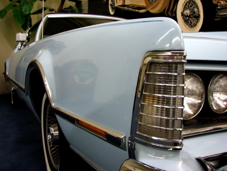 the front of a blue old fashioned car with its headlights on