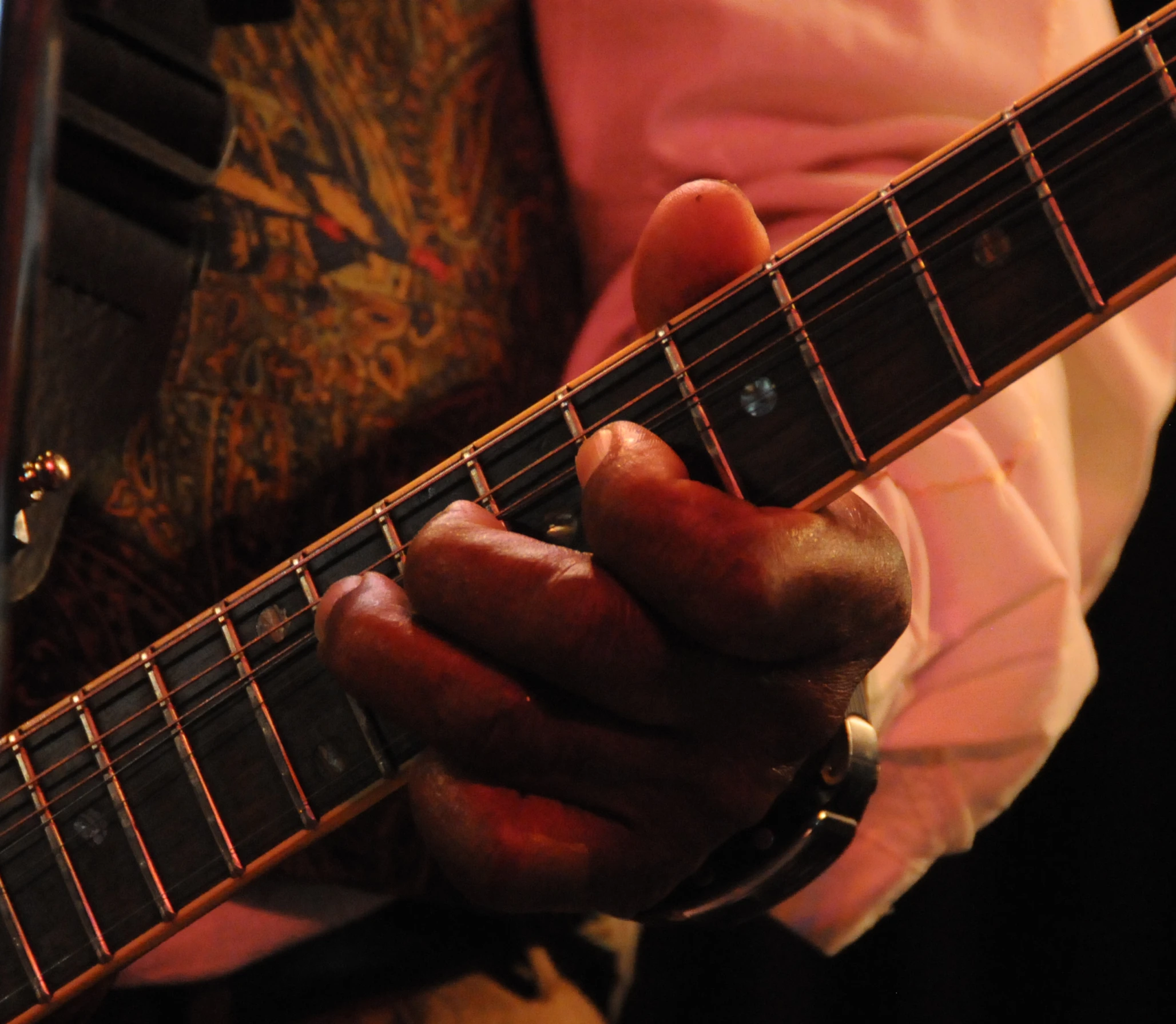 person with his hand on the neck of a guitar