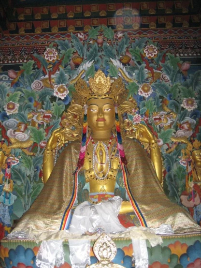 a very large golden statue in front of an elaborately painted wall