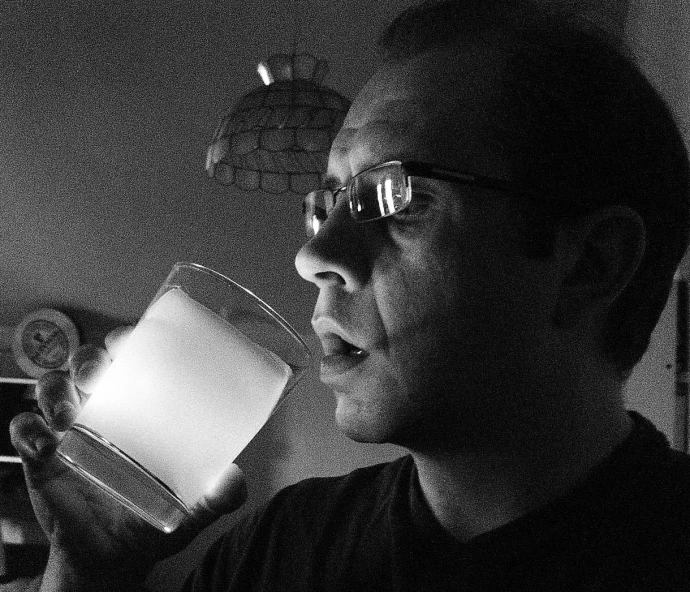 a man with glasses drinking out of a cup