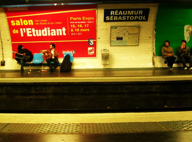 passengers sit on a bench at a train station