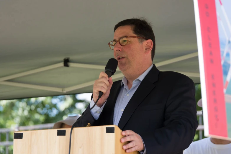 a man wearing glasses is speaking into a microphone