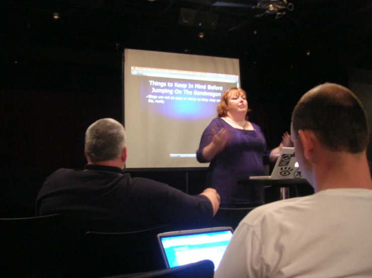 people in chairs at a presentation with a projector