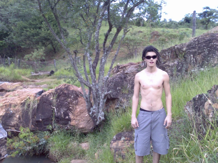 a man with  standing in grass with rocks