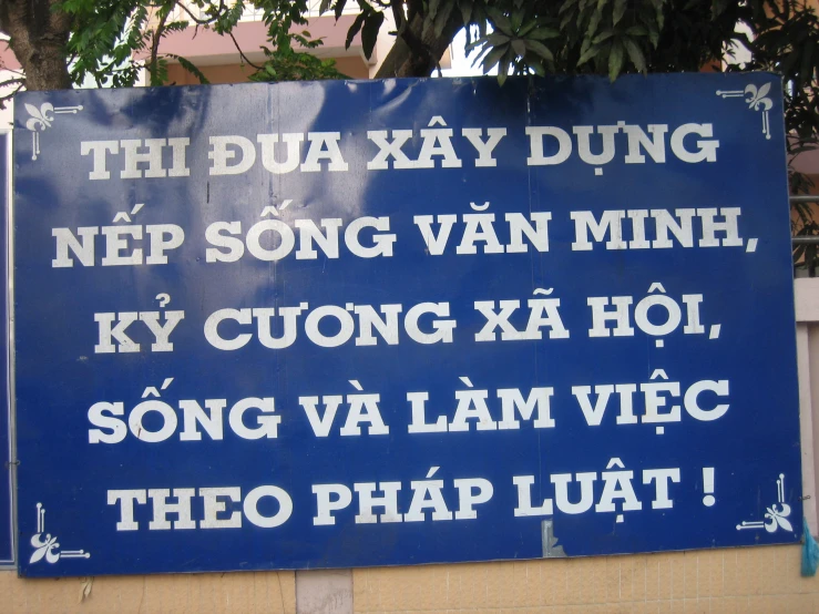blue sign with thai text that reads thuau kra yy nam hung near a building