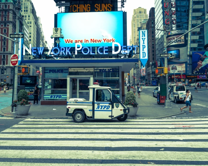 a police car sits in front of a street with big tvs