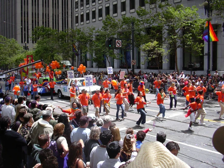 people in orange shirts marching down a city street