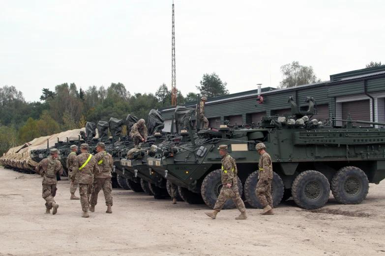 a group of soldiers walking past a group of military vehicles