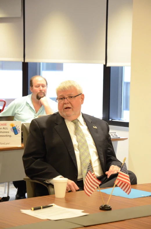 a man holding an american flag sitting at a desk