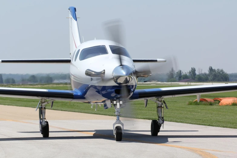 the small blue and white airplane is sitting on the runway