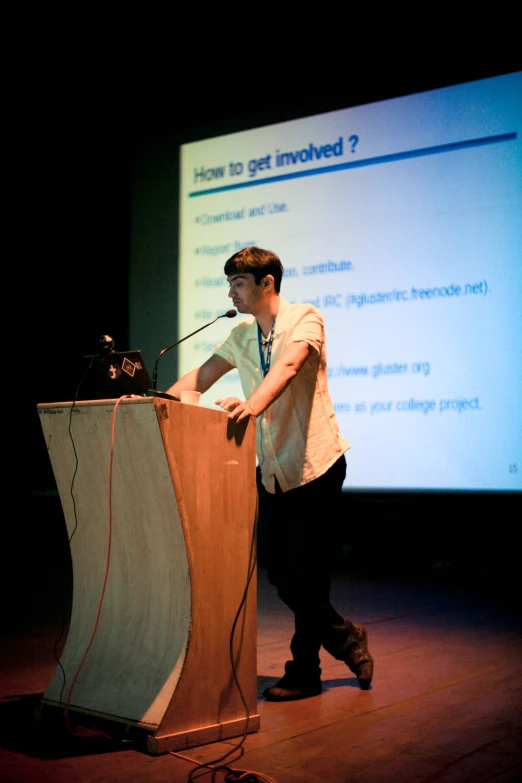 man at podium delivering a talk in front of large screen