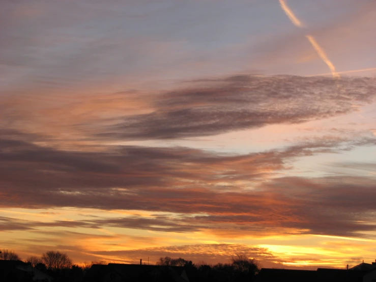 a plane is flying in the sky during the sunset