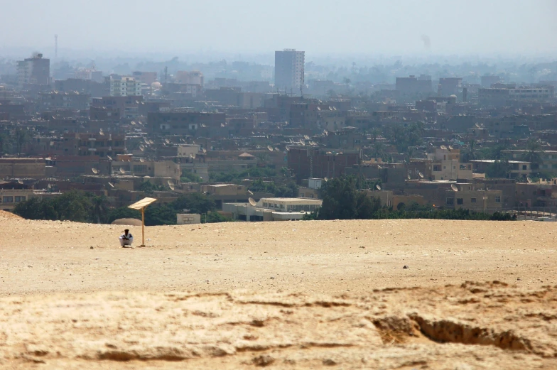 a man sitting under an umbrella near a sandy area