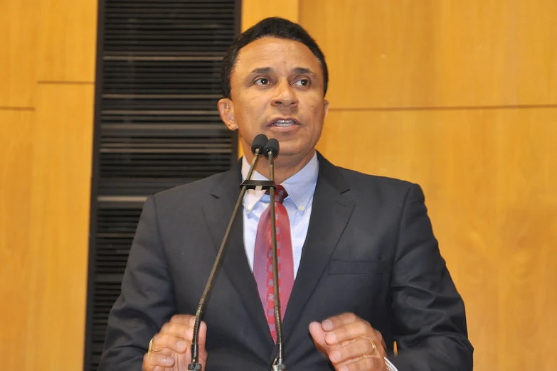 a man speaking at a podium with microphone in front of him