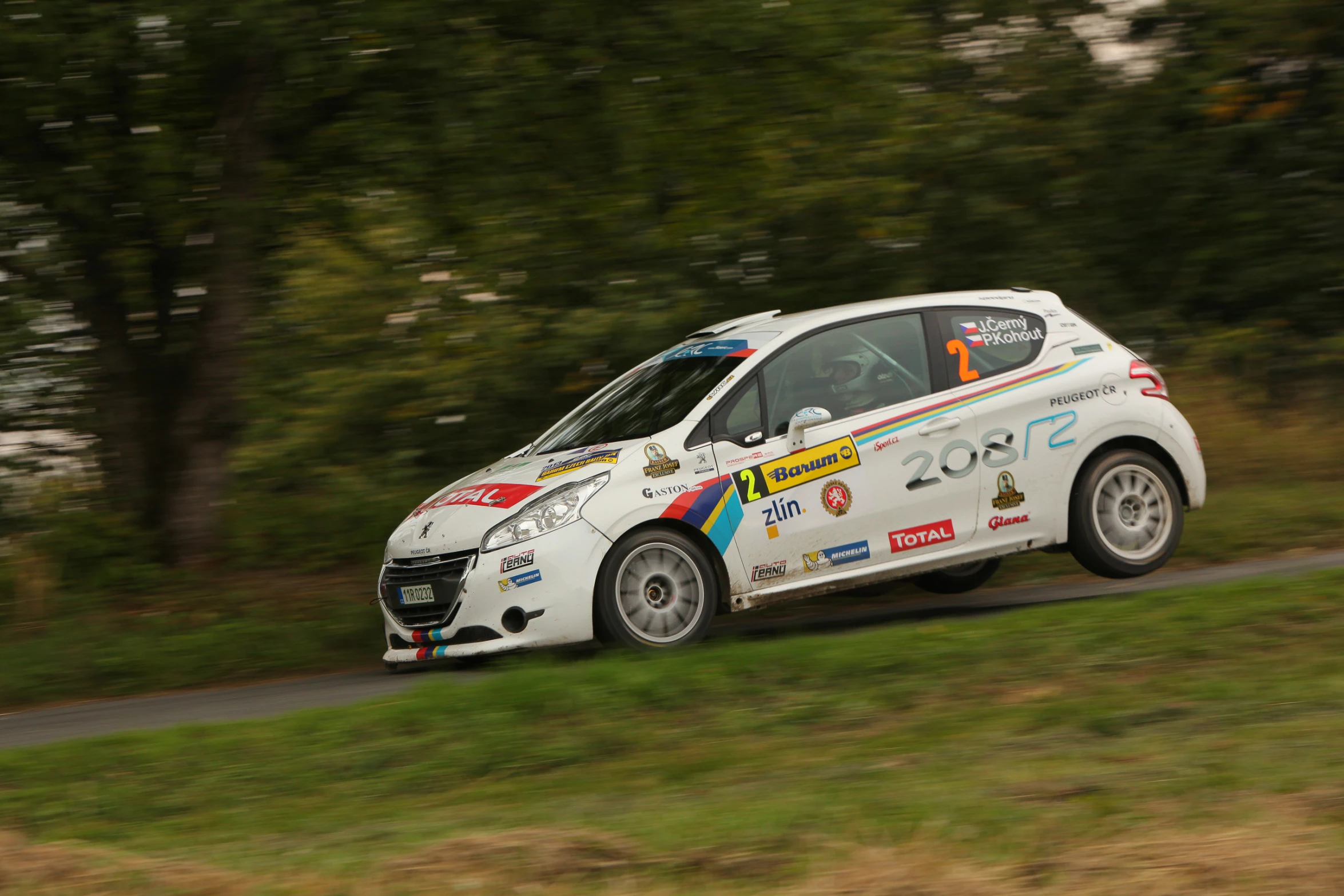 a car is racing on a road in the forest