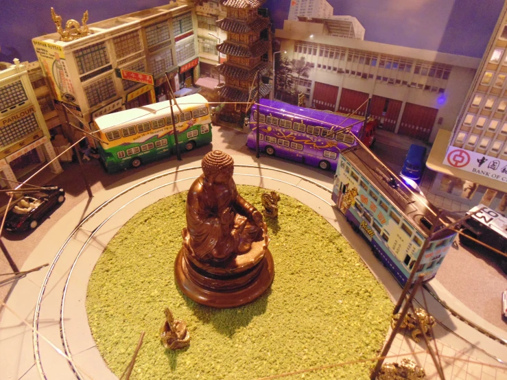 a small model town that includes a buddha statue and two buses