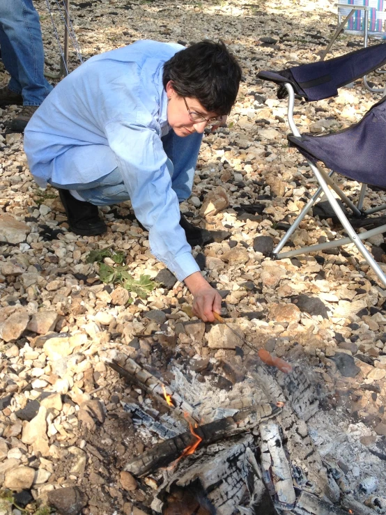 a man cooking food over an open fire while holding his head in his hands