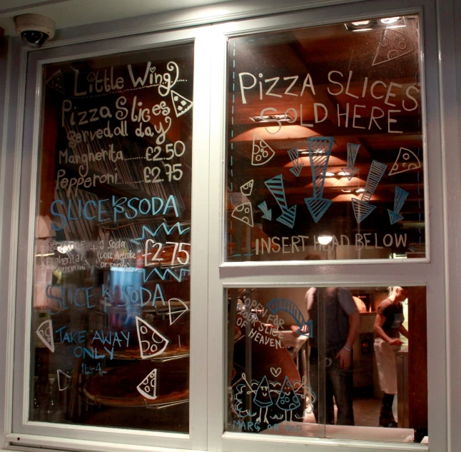 people are standing outside of a pizza shop