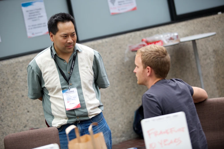 a man is talking to another man sitting at a table