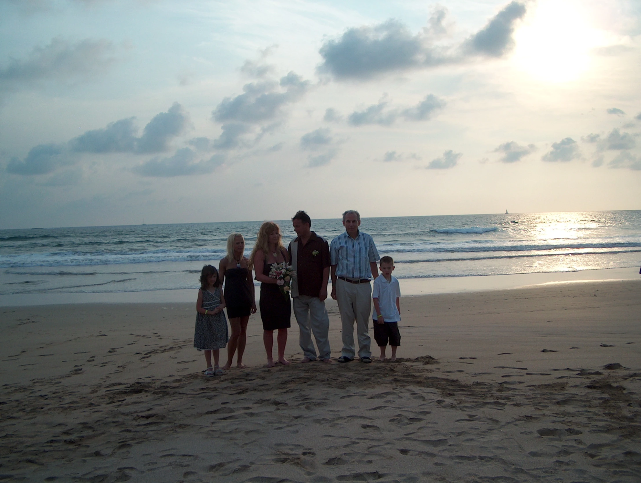 a family stands on the beach at sunset