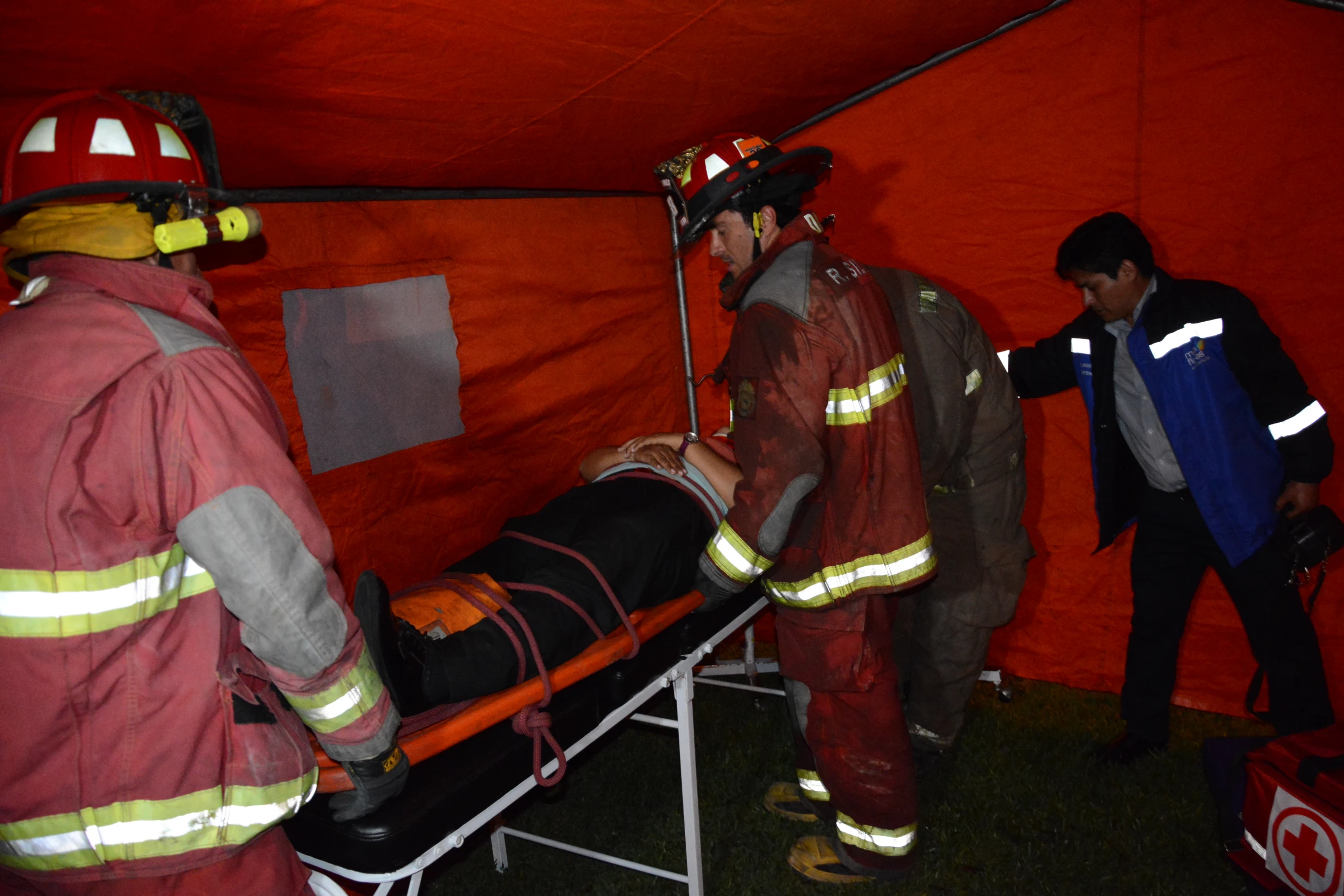 several firefighters working on a fire hose in a tent