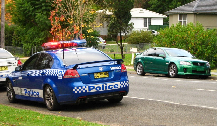 two police cars stopped at a traffic light on the road