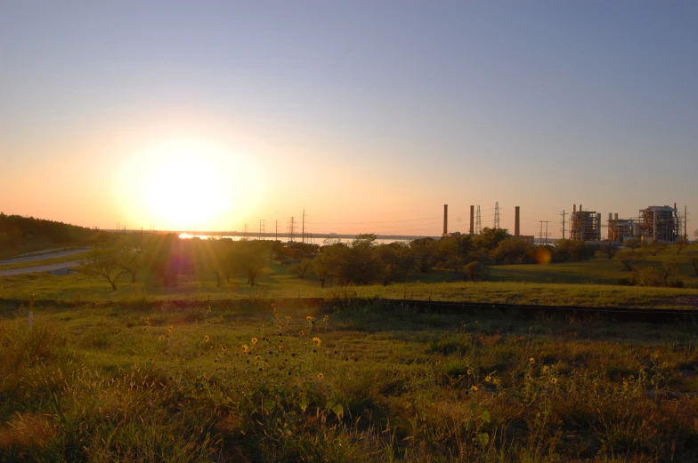 the sun is setting behind a large industrial area