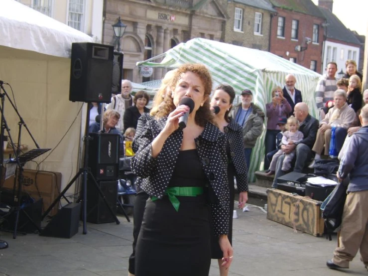 a woman in a black dress is holding a microphone